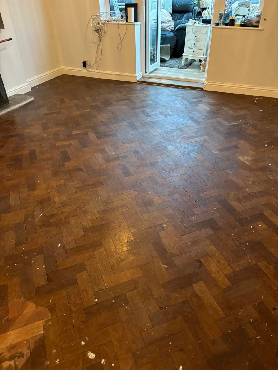 Herringbone parquet lounge floor before restoration, dull and marked